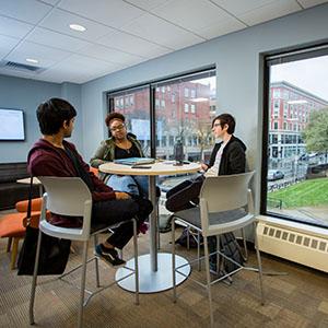 Three students sit around a table