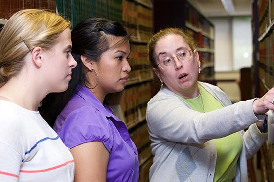 Librarian helping students locate materials 