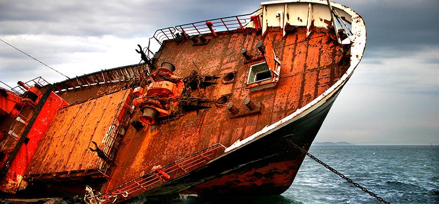 an image of a rusted, shipwrecked vessel resting on its side, jutting into the sky